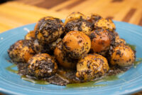 Bobalky with Poppyseeds and Honey piled on a blue plate, the dough balls glistening with glaze.