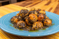 Bobalky with Poppyseeds and Honey piled on a teal plate, coated in dark poppyseed with honey pooling beneath.