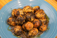 Bobalky with Poppyseeds and Honey piled on a blue plate, coated in dark poppy seeds with syrup pooling beneath