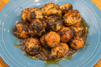 Bobalky with Poppyseeds and Honey piled on a blue plate, coated in poppy seeds with honey pooling beneath.