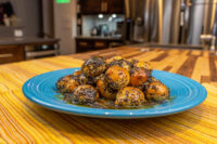 Bobalky with Poppyseeds and Honey: golden dough balls coated in poppyseed, glazed, piled on a blue plate.