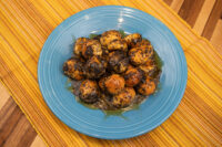 Blue plate piled with round bobalky dough balls coated in poppyseed and pooled honey