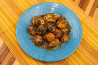 Bobalky with Poppyseeds and Honey piled on a blue plate, coated in dark poppyseed and glossy honey.