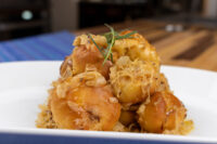 Bobalky with Sauerkraut Golden bobalky dumplings piled high, topped with sauerkraut and a rosemary sprig on a white plate.