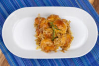 Bobalky with Sauerkraut Golden bobalky dumplings topped with sauerkraut and a herb sprig, served on a white oval plate.
