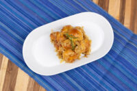 White oval plate of browned Bobalky with Sauerkraut, garnished with a herb sprig, on a blue striped runner.