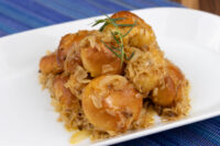 Bobalky with Sauerkraut Golden bobalky with sauerkraut piled on a white plate, garnished with a rosemary sprig.