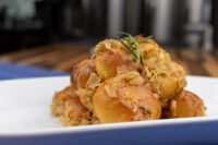 Golden Bobalky with Sauerkraut piled on a white plate, topped with browned sauerkraut strands and a sprig of herb.