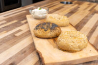 Creamy Spread with Garlic and Chives Bowl of Creamy Spread with Garlic and Chives beside seeded bread rolls on a wooden board.