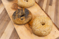 Seeded Bagels Trio Three seeded bagels topped with poppy, sesame, and mixed seeds on a wooden board