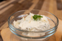 Creamy Spread with Garlic and Chives Glass bowl of Creamy Spread with Garlic and Chives, whipped and garnished with a parsley sprig, on wood
