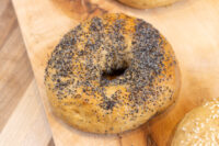 Bagel Recipe A poppy seed-topped bagel with a center hole resting on a wooden board.