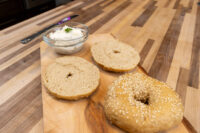 Creamy Spread with Garlic and Chives Small bowl of Creamy Spread with Garlic and Chives, herb-flecked, beside bagel halves on a wooden board
