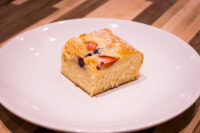 Bublanina (Czech Bubble Cake) Square slice of Bublanina (Czech Bubble Cake) with strawberries and dark berries, dusted with powdered sugar.