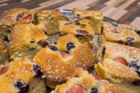 Bublanina (Czech Bubble Cake) Cut squares of Bublanina (Czech Bubble Cake) with strawberries and blueberries, dusted with powdered sugar.