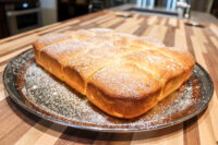 Buchty – Czech Sweet Filled Buns Golden Buchty – Czech Sweet Filled Buns, scored into squares and dusted with powdered sugar on a metal plate.