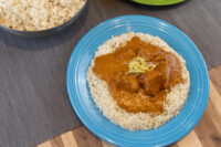 Butter Chicken Butter Chicken sauce with meat chunks over rice on a blue plate, garnished with lemon zest.