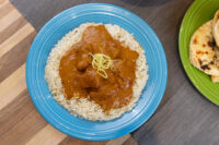 Butter Chicken Butter Chicken sauce with chicken pieces over rice on a blue plate, garnished with lemon zest.