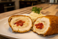 Chicken Cordon Bleu Sliced Chicken Cordon Bleu halves with red pimento filling, served with piped mashed potato and parsley.