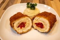 Chicken Cordon Bleu Sliced Chicken Cordon Bleu showing cheese and pimento filling, served with piped mashed potato and parsley.