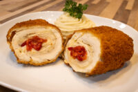 Chicken Cordon Bleu Sliced Chicken Cordon Bleu showing cheese and pimento filling, served with piped mashed potato on a white plate