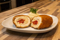 Chicken Cordon Bleu Sliced Chicken Cordon Bleu roll with melted cheese and red pepper filling, served with mashed potatoes and parsley.