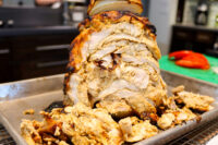Chicken Gyros Golden roasted Chicken Gyros loaf sliced open on a metal tray, with shredded meat piled beneath.