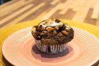 Chocolate Muffins Chocolate Muffins with chocolate chips and powdered sugar on a pink scalloped plate