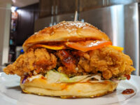 Crispy Chicken Sandwich with BBQ Sauce Crispy Chicken Sandwich with BBQ Sauce cut open, showing fried chicken, cheese, sauce, and slaw on a sesame bun.
