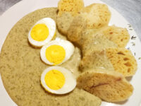 Czech Dill Sauce Koprová Omáčka Czech Dill Sauce Koprová Omáčka poured over dumpling slices with three halved eggs on a leaf-patterned plate