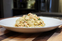 Fettuccine Alfredo with Salmon Plated Fettuccine Alfredo with Salmon, creamy pasta with pink salmon pieces and peas on a white dish.