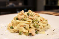 Fettuccine Alfredo with Salmon Plated Fettuccine Alfredo with Salmon, peas and cracked pepper in creamy sauce on white dish.