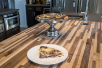 Slice of Frgal Kolach with Plum Filling on a plate, rest of the kolach on a cake stand behind it.