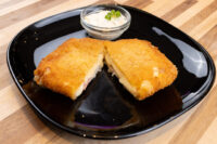 Fried Cheese with Ham Fried Cheese with Ham cut in half showing melted cheese and ham, served with a creamy dip on a black plate