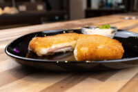 Fried Cheese with Ham Fried Cheese with Ham cut in half showing melted cheese and ham, served on a black plate with dip.