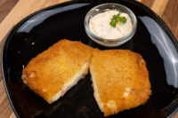 Fried Cheese with Ham Fried Cheese with Ham, breaded and fried, cut in half showing melted cheese and ham, with a creamy dip.
