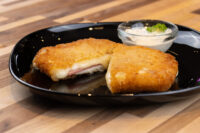 Fried Cheese with Ham Fried Cheese with Ham, breaded and fried, sliced open to show melted cheese and ham, served with a creamy dip.