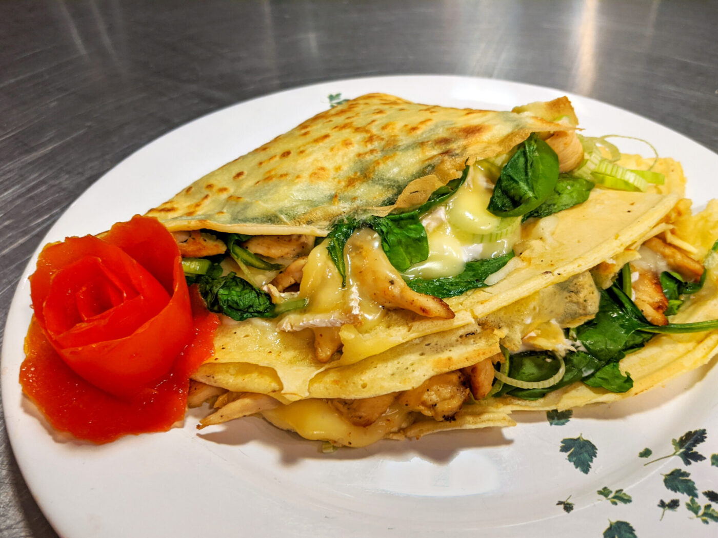 Galettes with Chicken, Spinach, and Brie Cheese Galettes with Chicken, Spinach, and Brie Cheese folded into a wedge on a white plate with a tomato rose garnish.