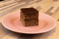 Gingerbread Bars A square Gingerbread Bar with dark chocolate coating on a pink scalloped plate.