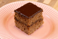 Gingerbread Bars A square Gingerbread Bars slice with dark chocolate coating on a pink ridged plate.