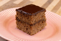 Gingerbread Bars Square Gingerbread Bar with chocolate glaze and dark filling between two layers, on a pink plate