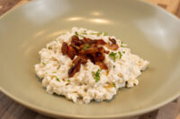 Halušky with Bryndza Cheese Substitution Bowl of Halušky with Bryndza Cheese Substitution topped with crispy bacon and chopped herbs