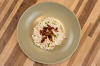 Bowl of Halušky with Bryndza Cheese Substitution topped with crispy bacon and herbs on a wooden table