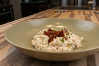 Halušky with Bryndza Cheese Substitution Halušky with Bryndza Cheese Substitution in a green bowl, topped with crispy onions and herbs.