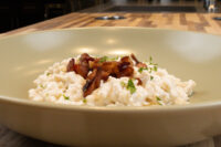 Bowl of Halušky with Bryndza Cheese Substitution topped with crispy bacon bits and chopped herbs.