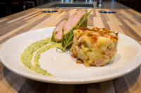 Herb-crusted Pork Tenderloin Sliced Herb-crusted Pork Tenderloin with rosemary, served with a potato cake and green herb sauce.
