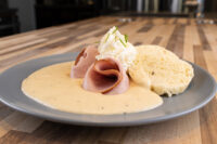 Creamy Horseradish Sauce Křenová Omáčka on a plate with rolled ham, cream cheese, and cornbread.