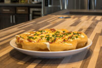 Langos Langos topped with melted cheese, red sauce, and chopped chives, served on a white oval plate.