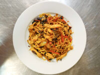 Lo Mein with Chicken White bowl of Lo Mein with Chicken with noodles, chicken pieces, red peppers, and dark mushrooms