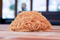 Lo Mein with Chicken A mound of pale lo mein noodles for Lo Mein with Chicken resting on a wooden surface.